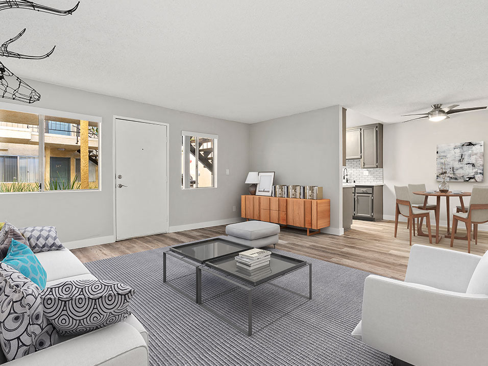 A living room with a grey carpet and a glass coffee table.