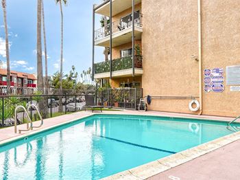 A swimming pool in front of a building with a fence around it.