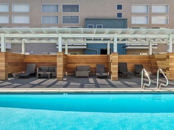 A pool area with sun loungers and a building in the background.