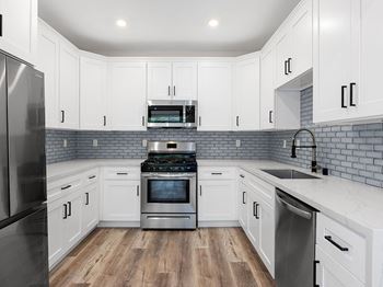 A kitchen with white cabinets and a brick backsplash.