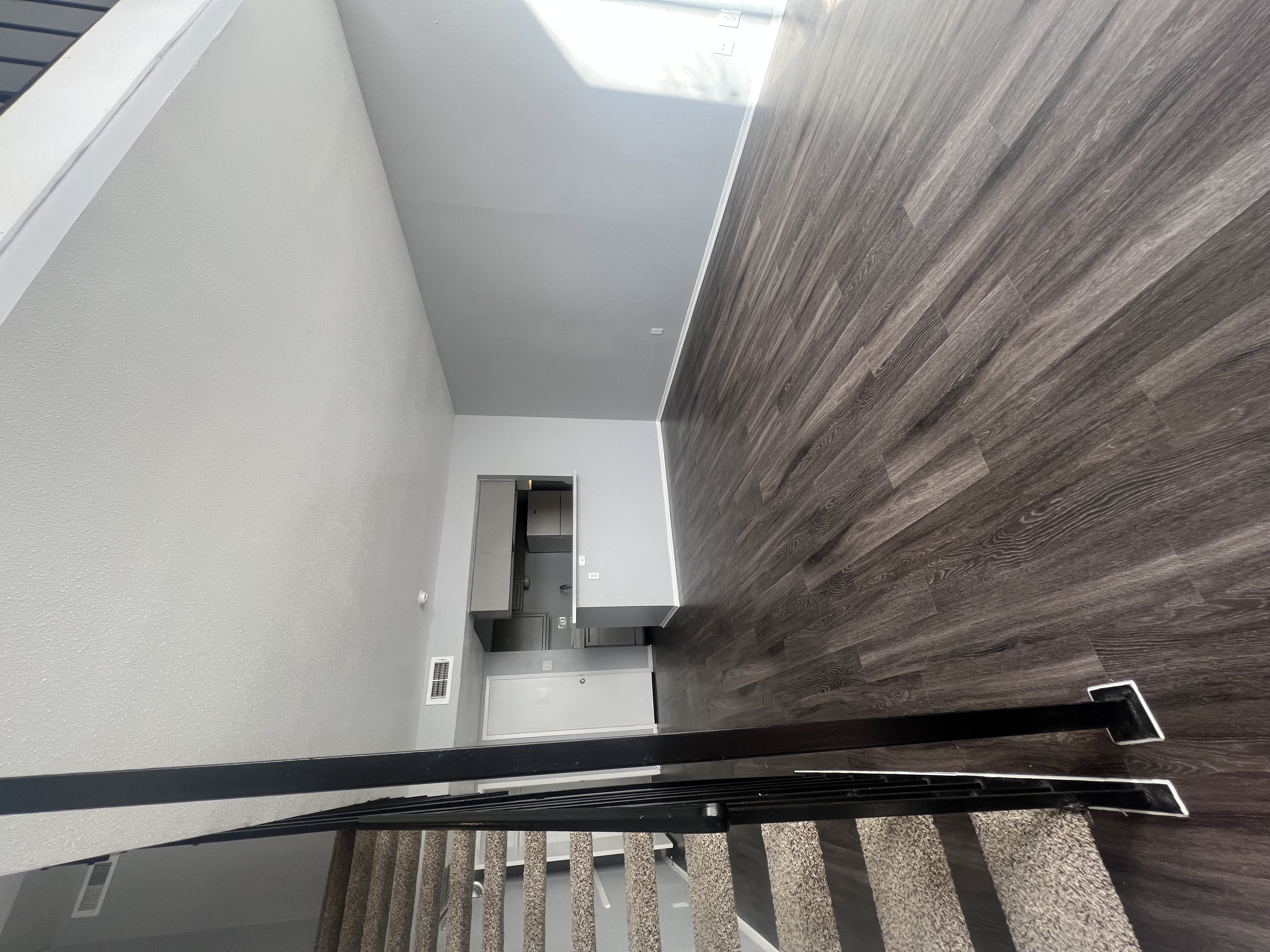 A staircase with a wooden handrail and a carpeted runner.