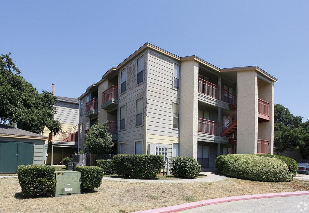 an apartment building with multiple balconies and manicured bushes