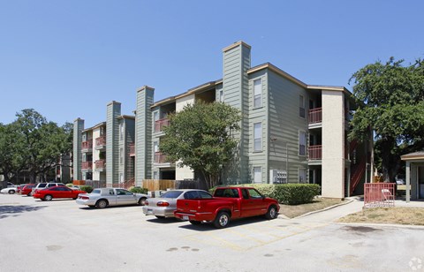 a row of apartment buildings with cars parked in front of them