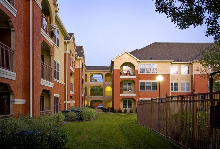 a row of brick apartment buildings with a green yard