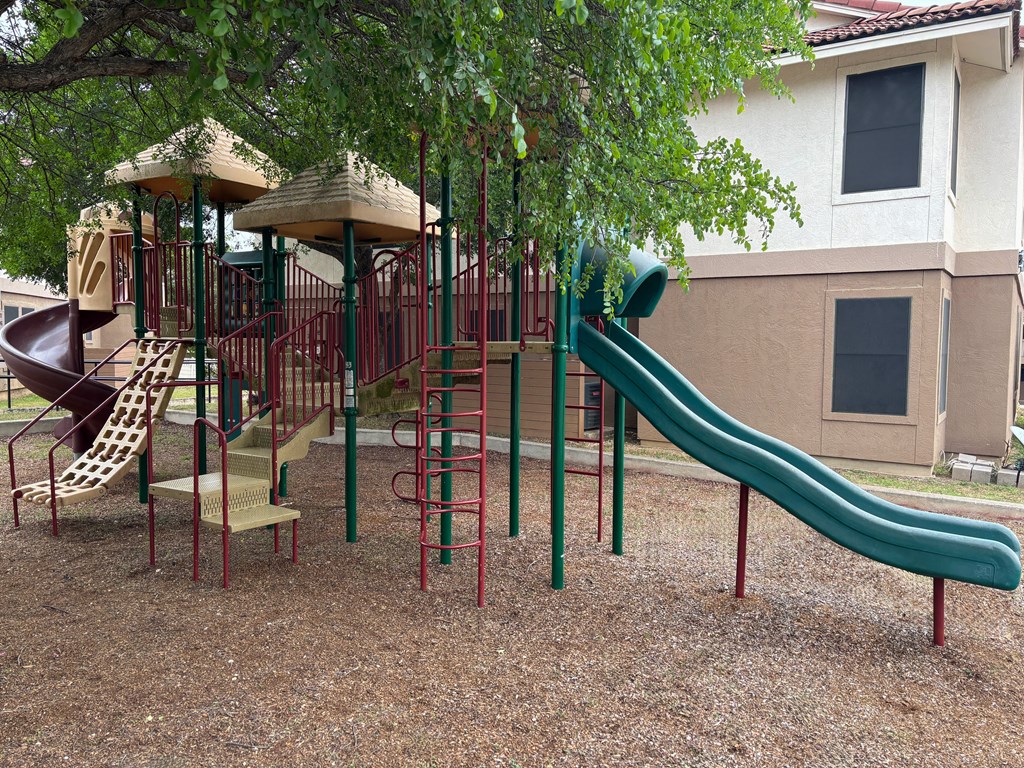 A playground with a green slide and a red and green structure.