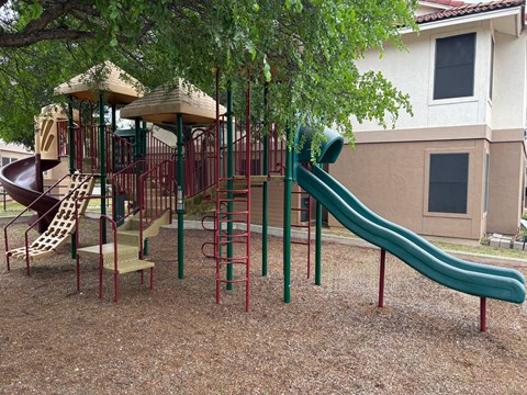 A playground with a green slide and a red and green structure.