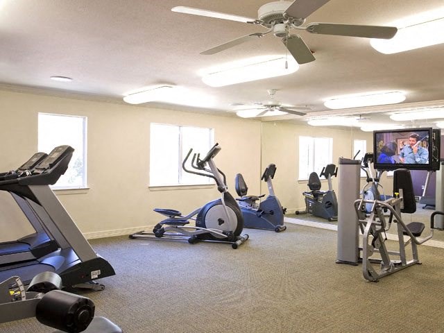a gym with various exercise equipment and a tv