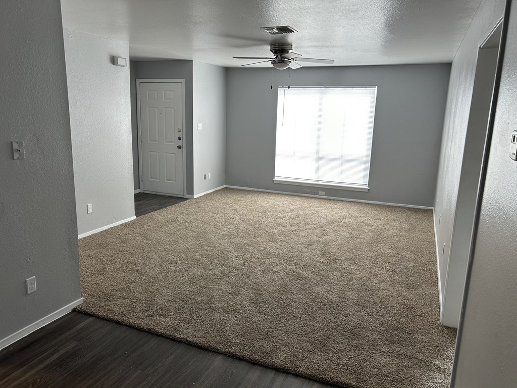 an empty living room with a rug and a ceiling fan