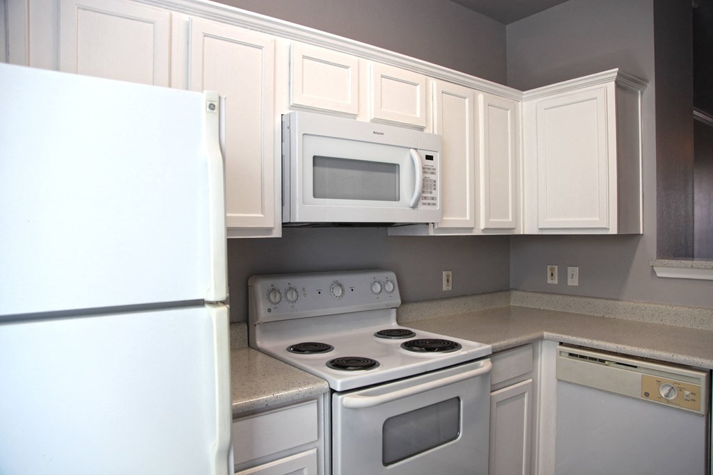 a kitchen with white cabinets and appliances and a white refrigerator