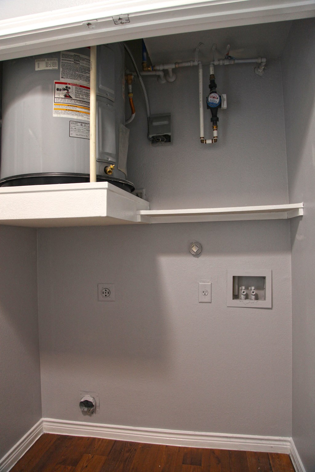 an empty room with a heater and a wall with a shelf