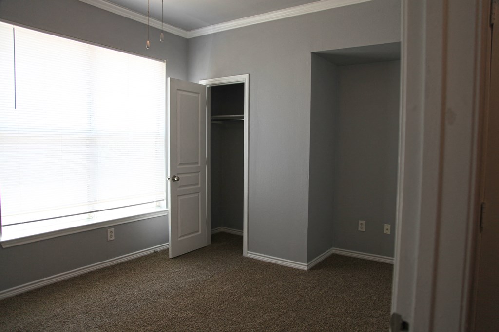 a bedroom with a large window and a door to a closet