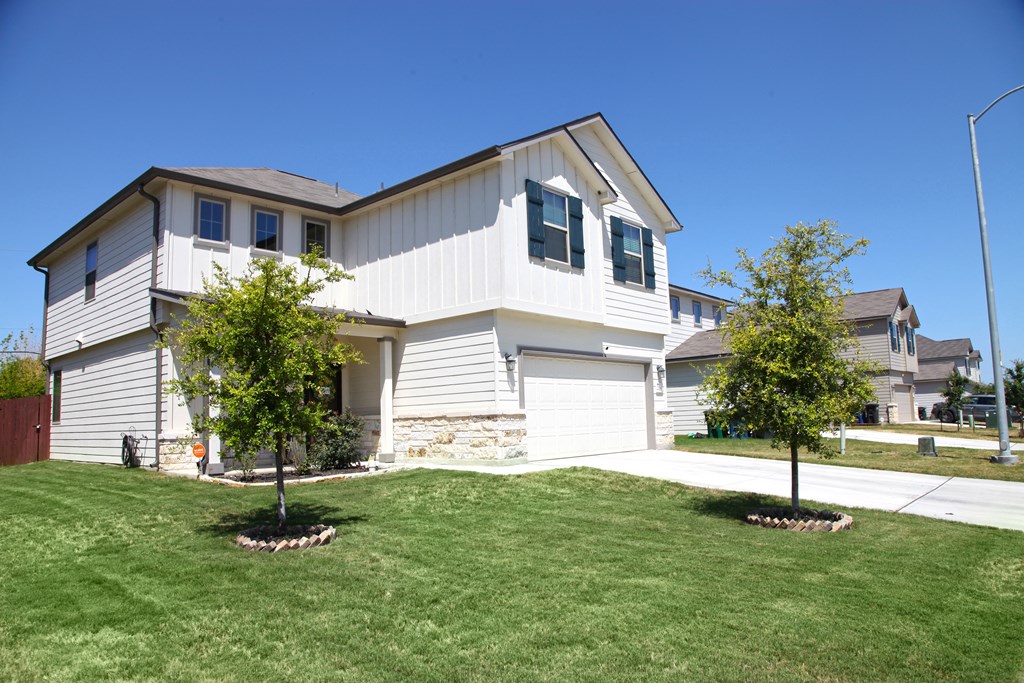 a white house with a lawn and trees in front of it