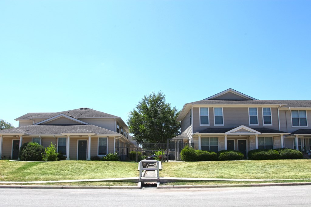 two houses on a lawn in front of a street