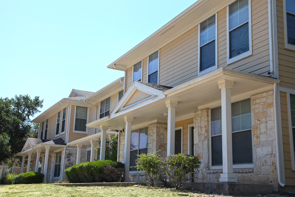 a row of homes with stone and tan siding and white columns