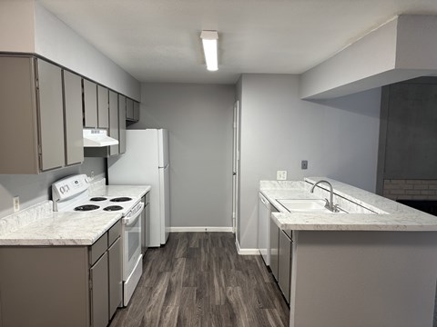 A kitchen with a white stove top oven and a white refrigerator.