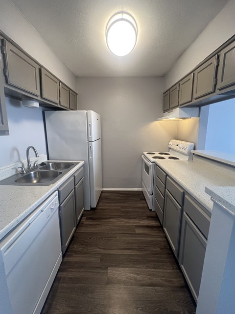 A kitchen with white cabinets and a white fridge.