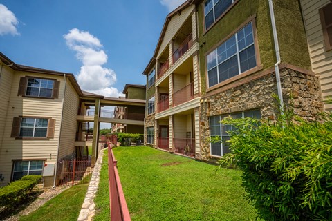 Apartment complex with a red pathway leading to the front door.