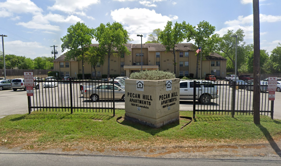 a dumpster in front of a fence and an apartment building