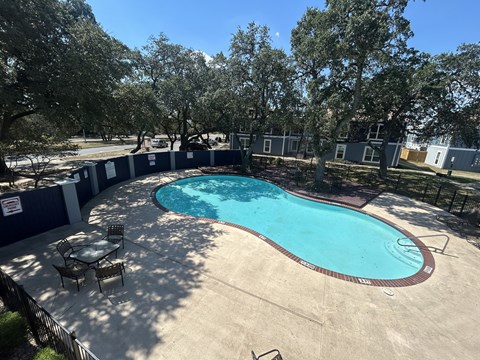 A round above ground pool with a table and chairs around it.