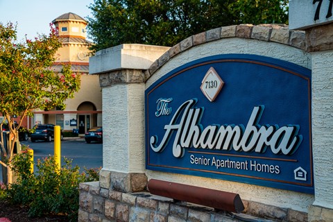 A sign for The Alhambra Senior Apartment Homes is displayed in front of a building.