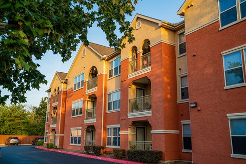 A red brick apartment building with a tree in front.