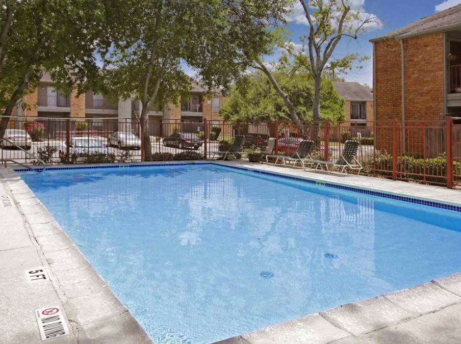 A swimming pool surrounded by trees and chairs.