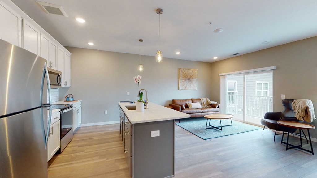 a kitchen and living room with a refrigerator and a sink