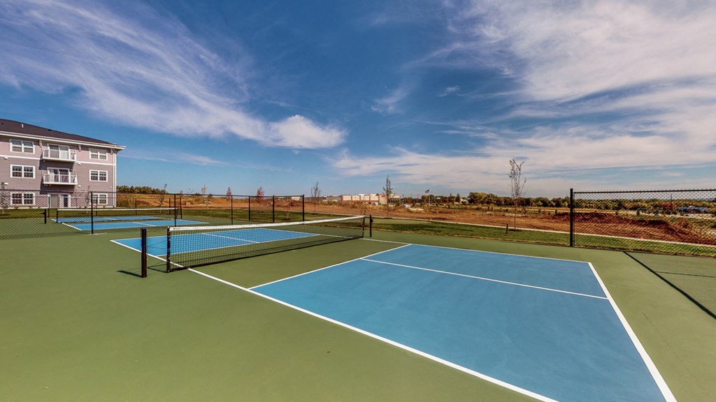 two tennis courts with apartments in the background