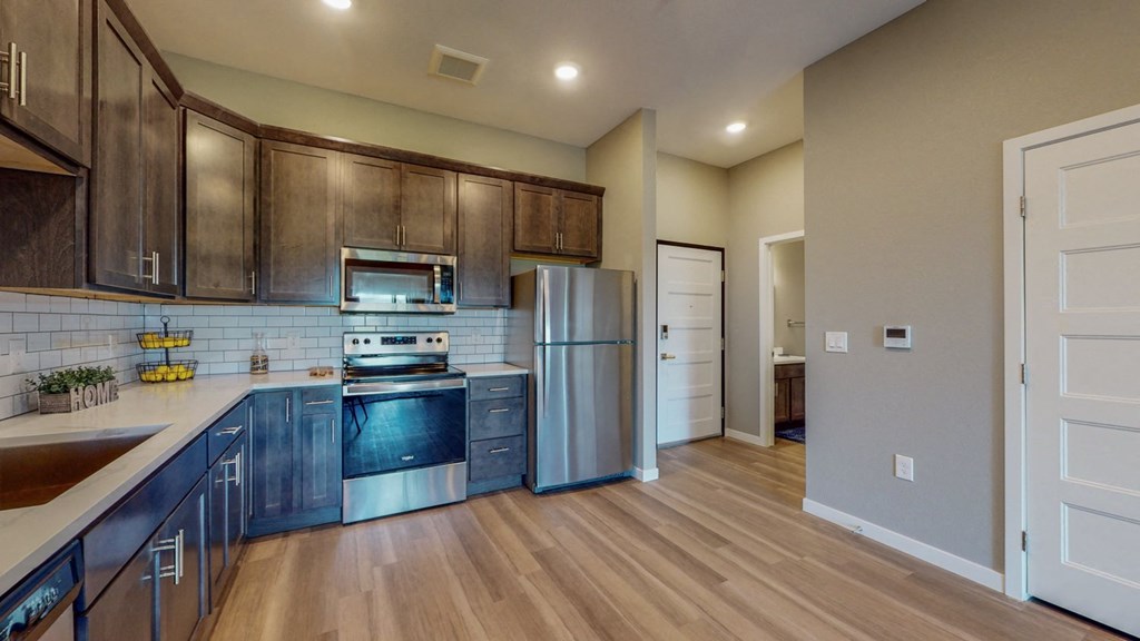 an empty kitchen with wood flooring and stainless steel appliances