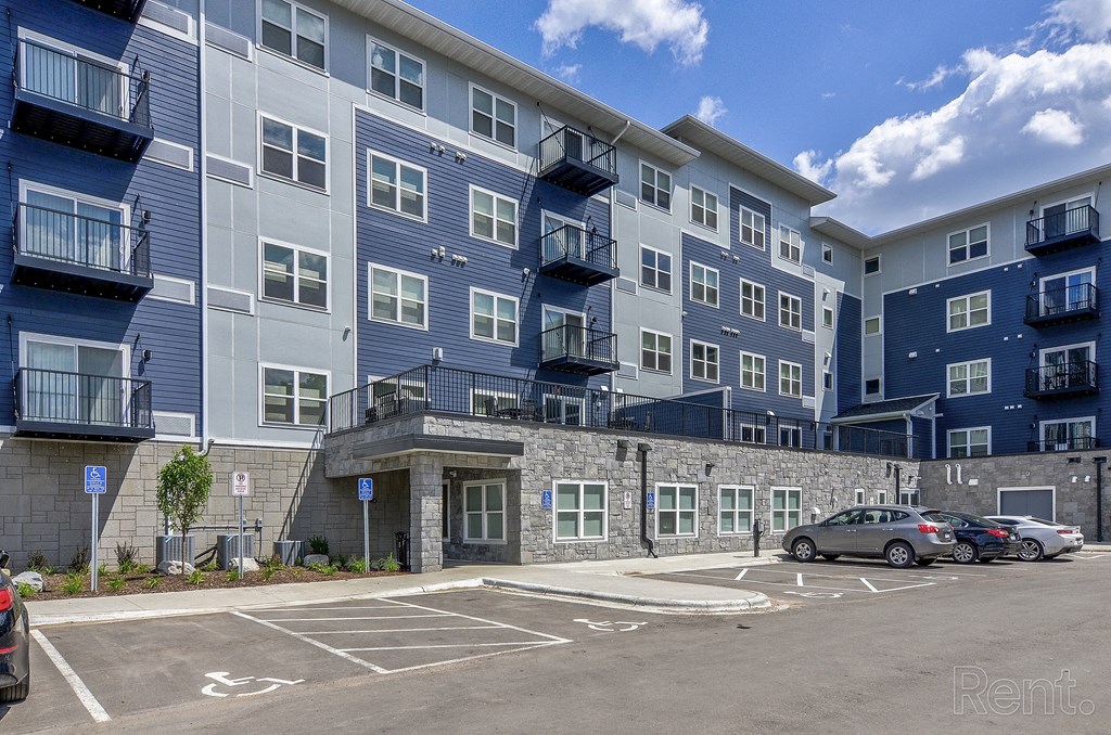 an exterior view of an apartment building with cars parked in a parking lot