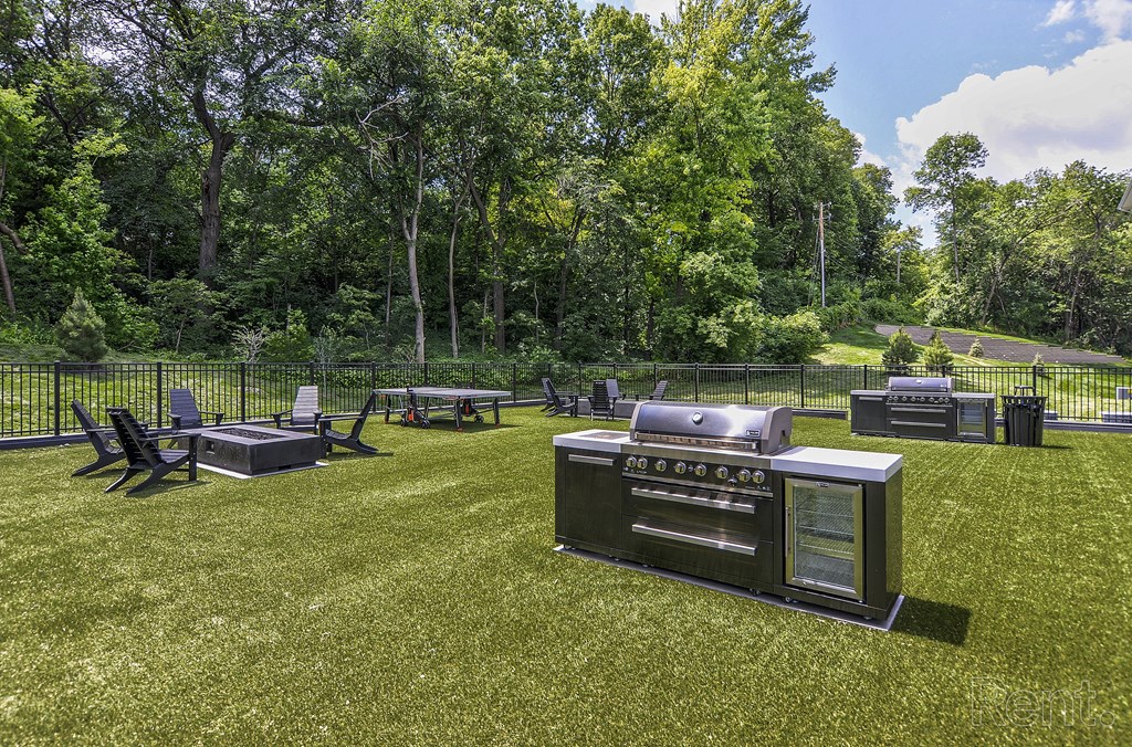 a backyard with a barbecue grill and picnic tables