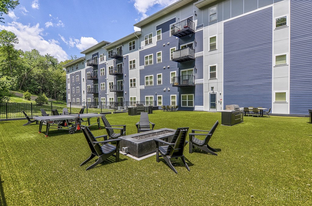 a courtyard with tables and chairs in front of an apartment building