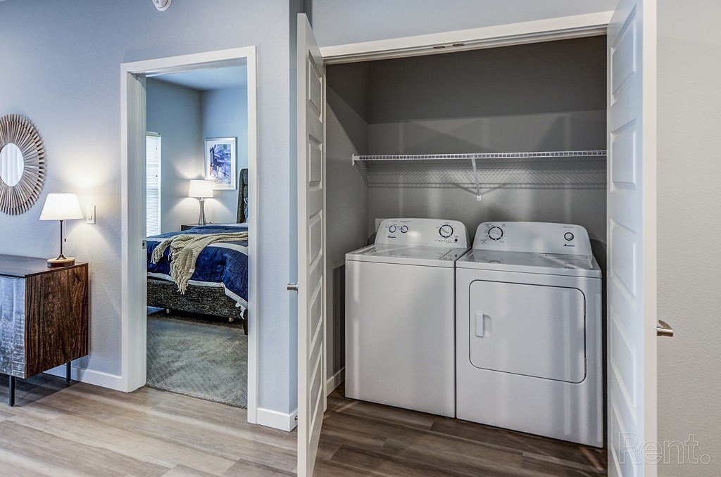 a bedroom with a washer and dryer and a closet with a bed