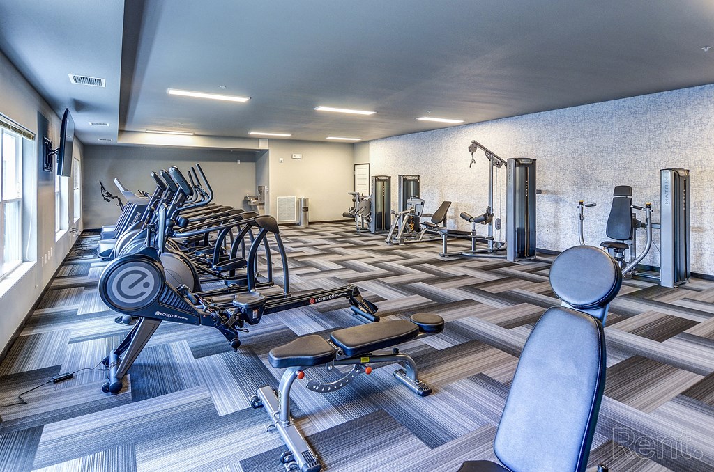 a gym with cardio machines and weights on a checkered floor