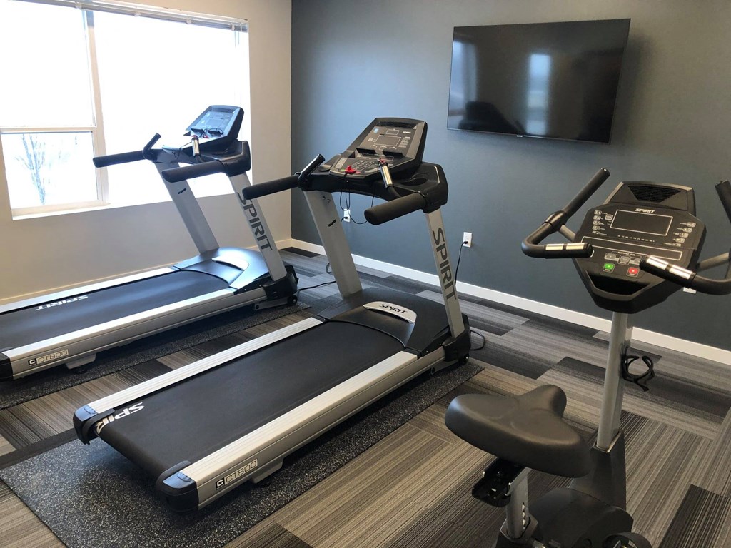 a gym with two treadmills and a tv