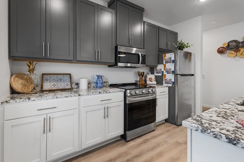 A kitchen with black and white cabinets and a granite countertop.