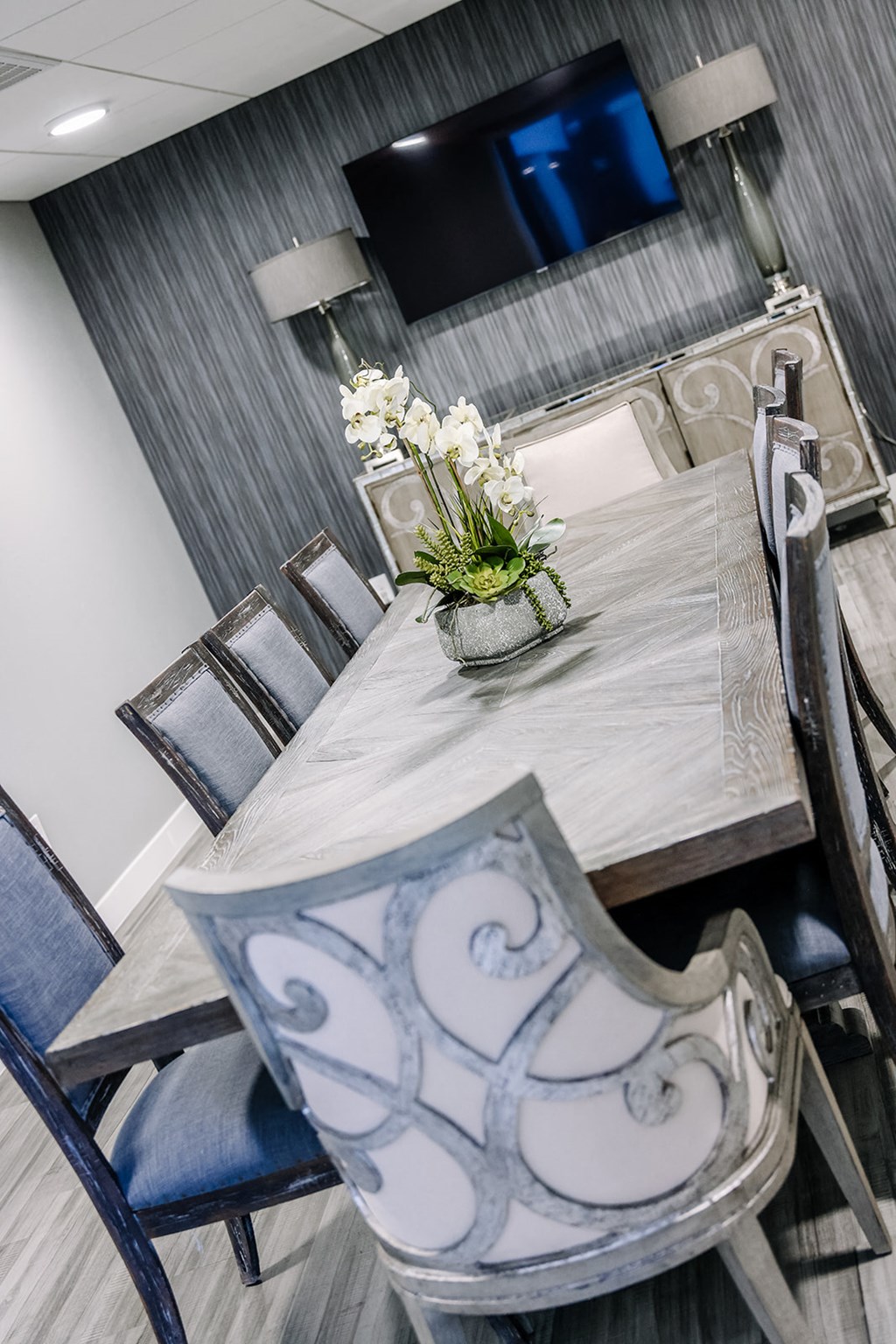 a dining table with chairs and a vase with flowers on it