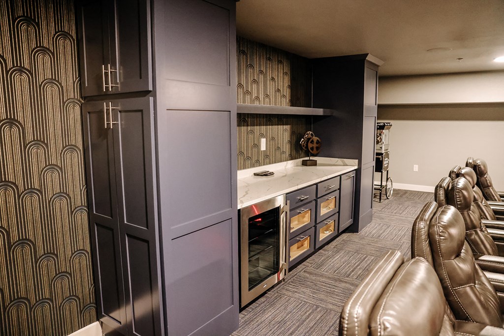 a home theater room with leather chairs and a kitchen