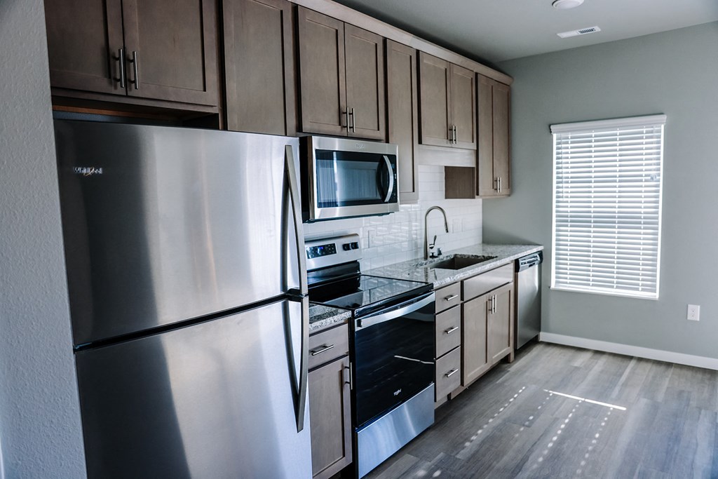 an empty kitchen with stainless steel appliances and wooden cabinets
