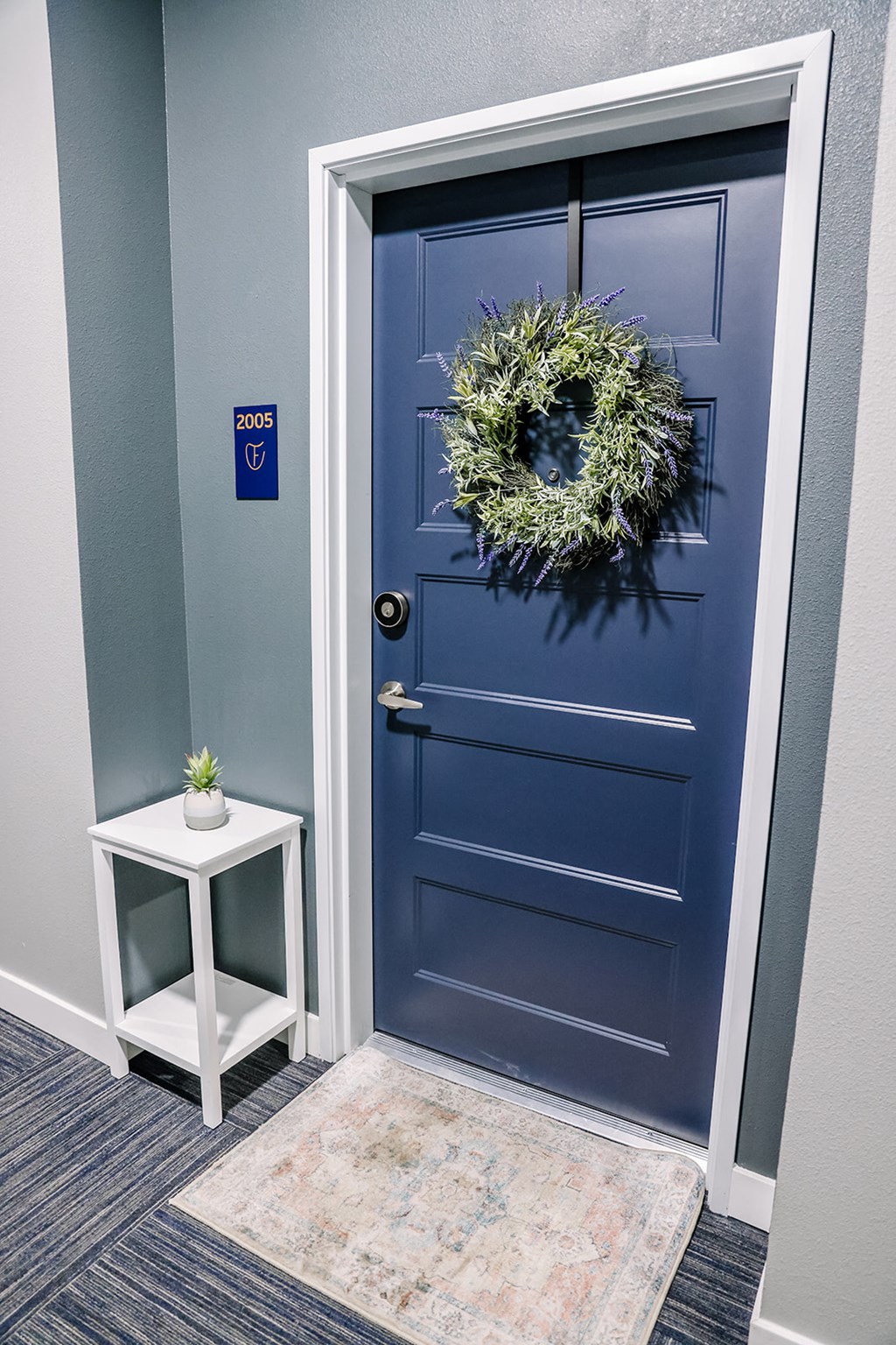 a blue door with a wreath on it and a side table
