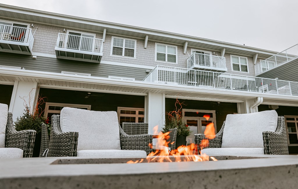a patio with chairs and a fire pit in front of a house