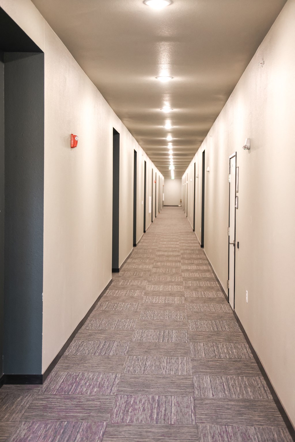 a long corridor with white walls and doors and a tiled floor