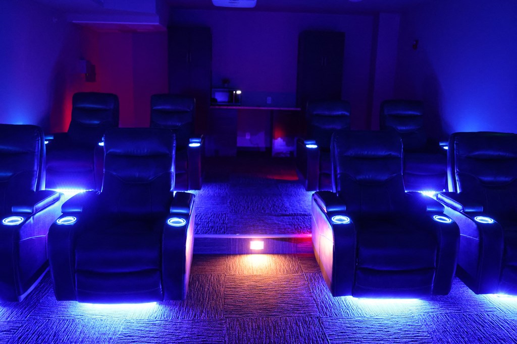 a dark theater room with blue lighting and chairs