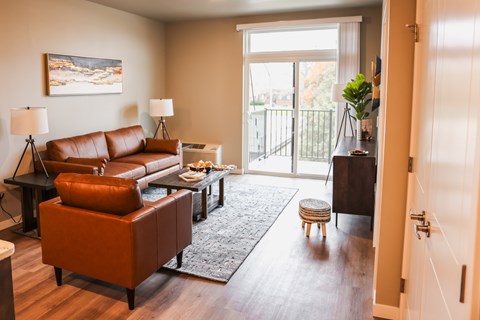A living room with a brown couch and a painting on the wall.