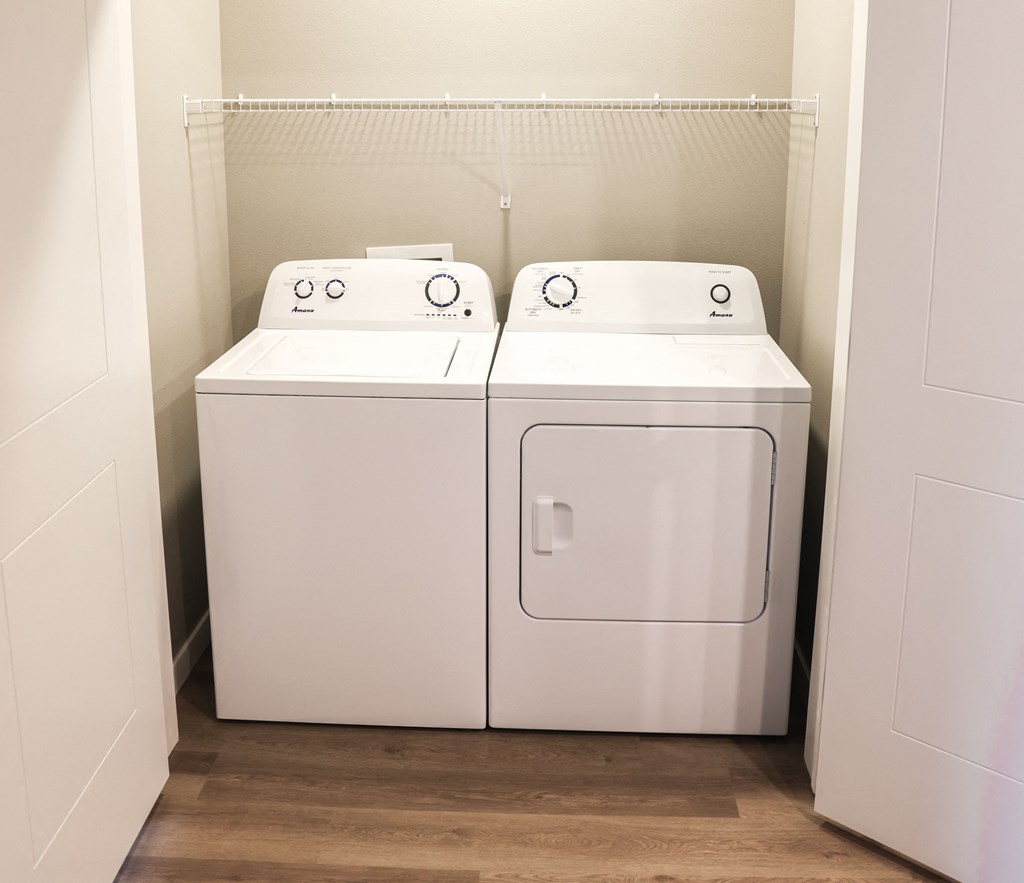 a washer and dryer in a room with wood floors and a white wall