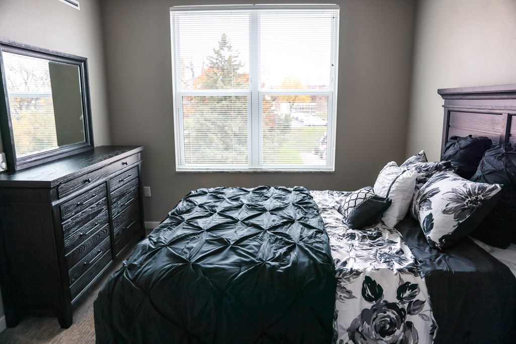 a bedroom with a bed and a dresser and a window