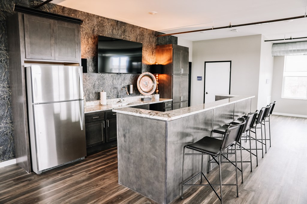 a kitchen with stainless steel appliances and a bar with chairs