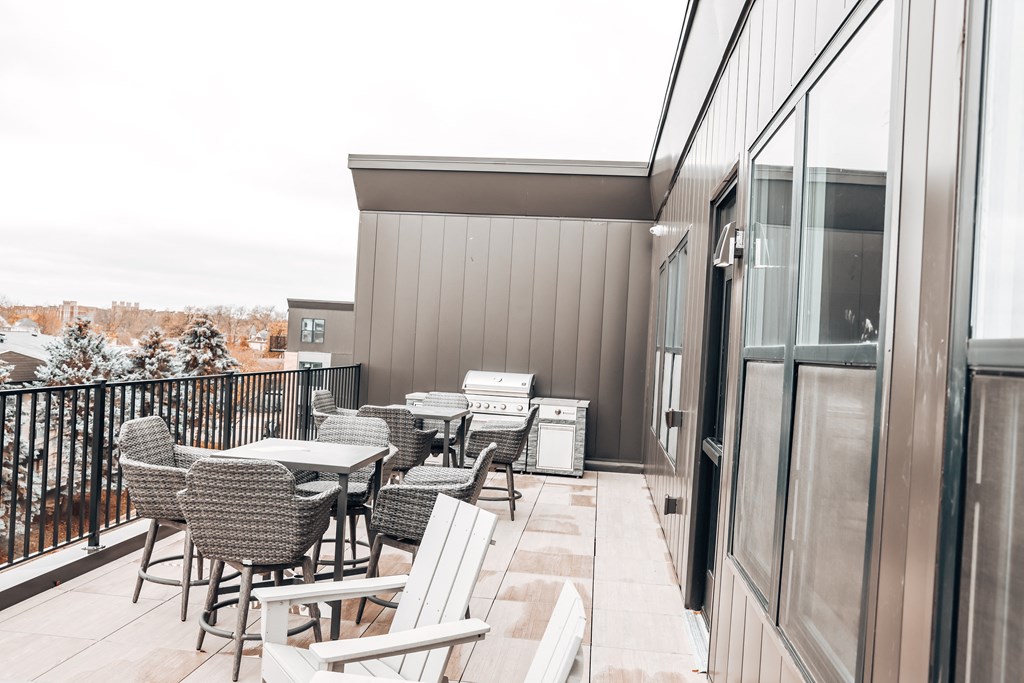 a patio with tables and chairs and a grill on a balcony