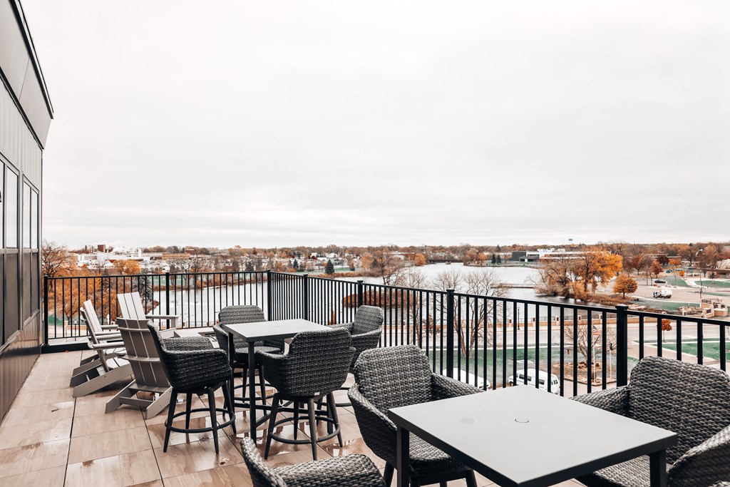 a balcony with tables and chairs and a view of the city