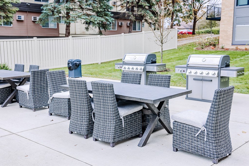 a patio with a table and chairs and two gas grills